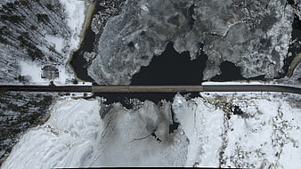 Aerial view of bridge over frozen river in winter forest
