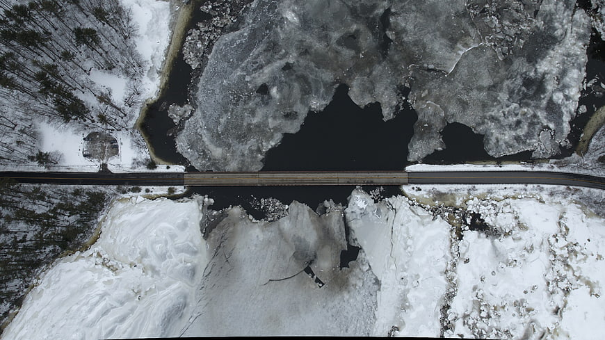 Aerial view of bridge over frozen river in winter forest