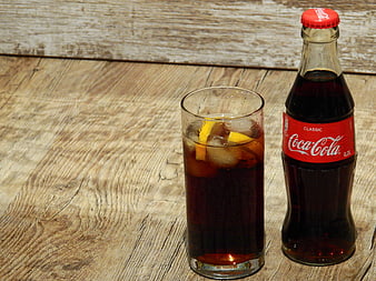 Coca-Cola bottle and iced glass on rustic wooden table