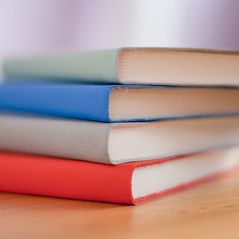 Stack of colorful hardcover books on wooden table