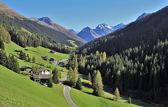 Alpine Village Landscape With Winding Road And Snow-Capped Peaks