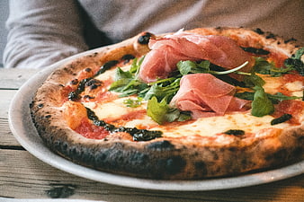 Close-up of Neapolitan pizza with prosciutto and arugula