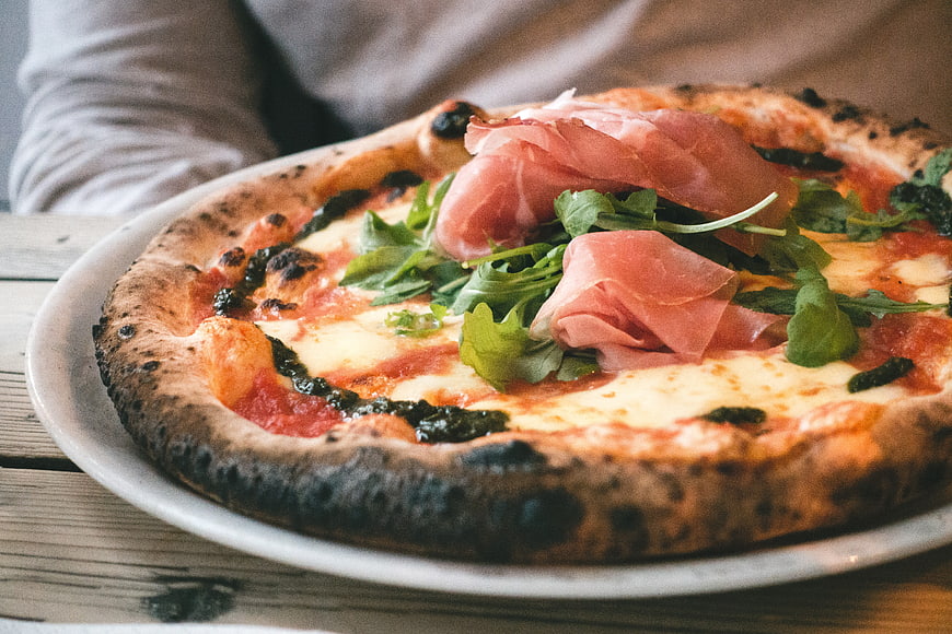 Close-up of Neapolitan pizza with prosciutto and arugula