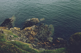 Aerial View of Rocky Coastline with Green Cliffs and Ocean
