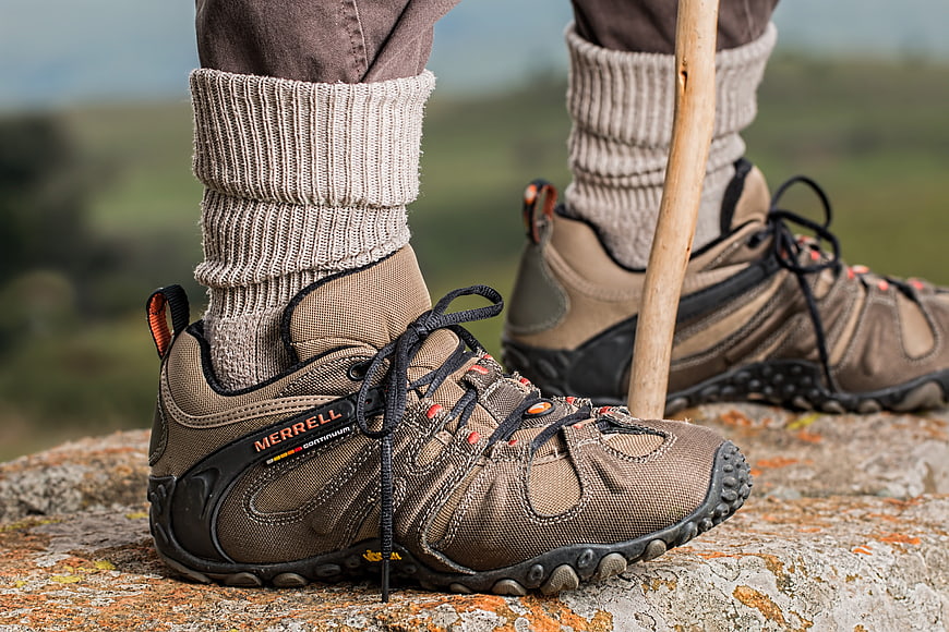 Hiking boots on rocky terrain with walking stick
