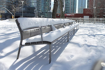 Snow-covered park bench in urban winter setting