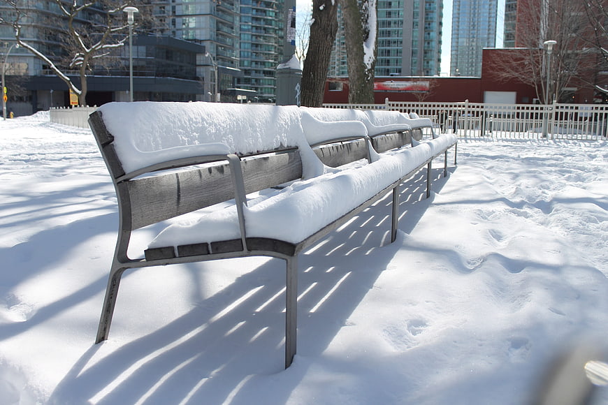 Snow-covered park bench in urban winter setting