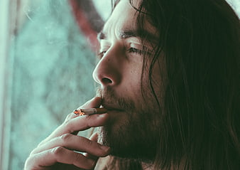 Close-up of man with long hair smoking cigarette