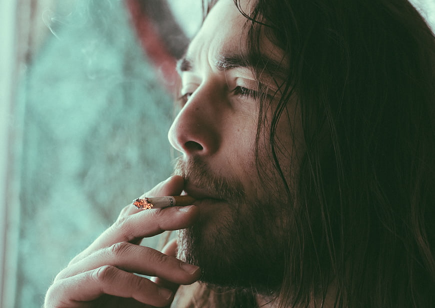 Close-up of man with long hair smoking cigarette