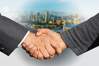 Business handshake with blurred city skyline background