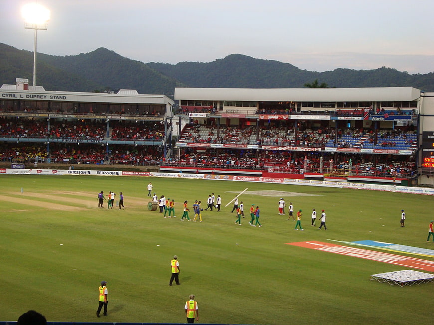 Cricket match preparation at stadium with crowd and mountains