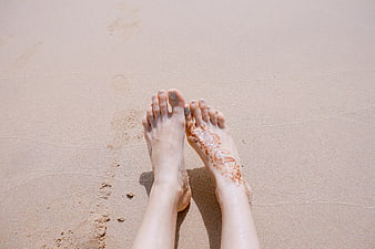 Woman's feet with henna on sandy beach