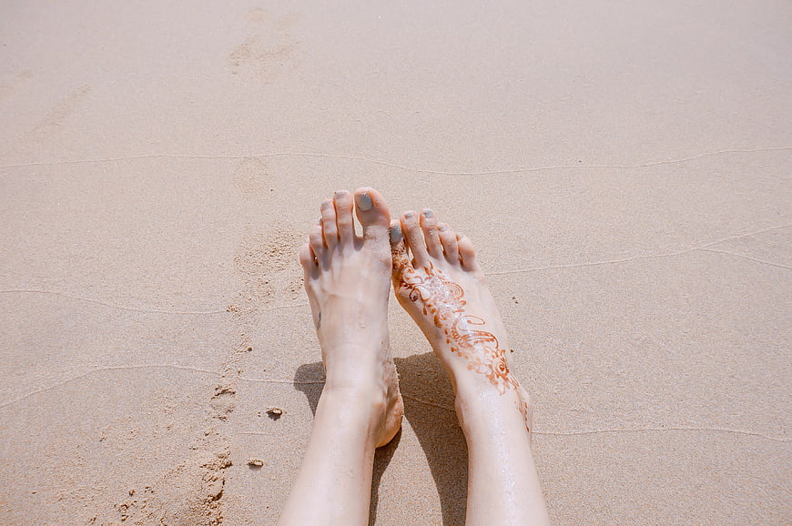 Woman's feet with henna on sandy beach