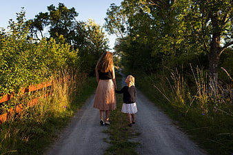 Mother and daughter walking hand in hand on a country path