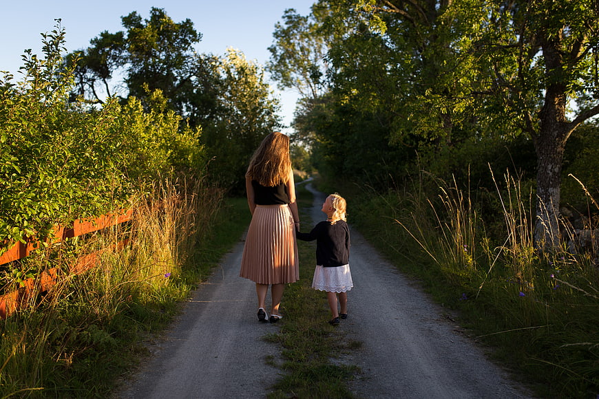 Mother and daughter walking hand in hand on a country path