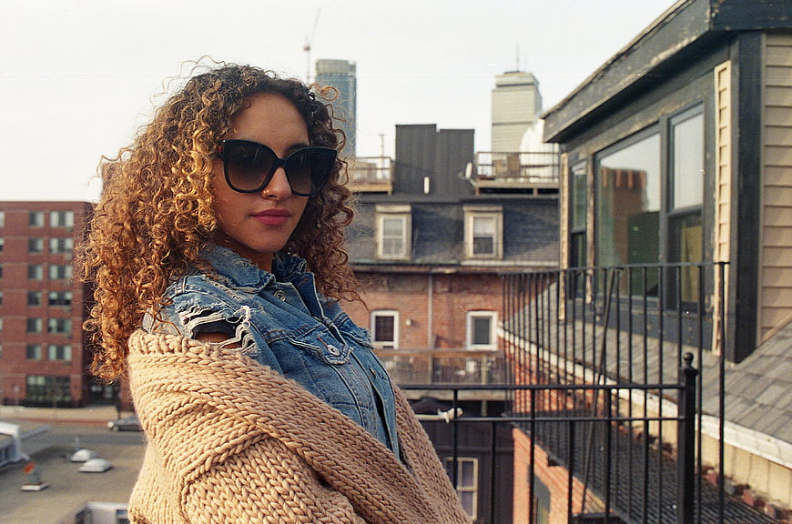 Stylish Woman with Curly Hair and Sunglasses on Urban Rooftop