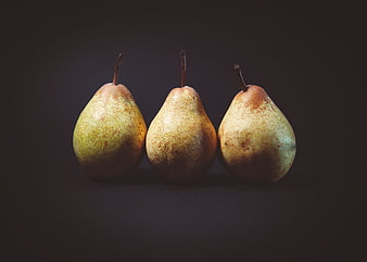 Three ripe pears in a row on a dark background