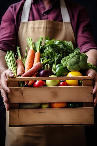 Farmer holding wooden crate of fresh organic vegetables