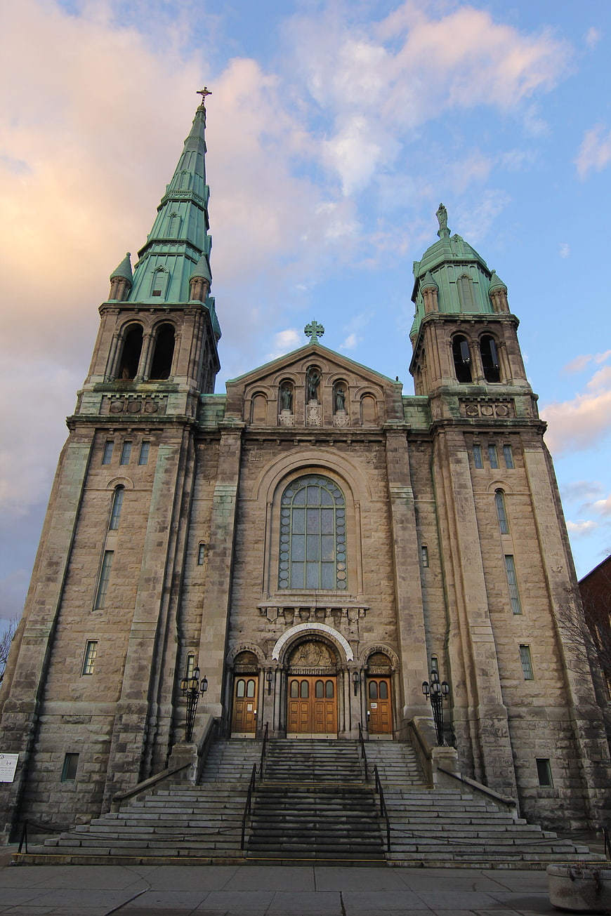 Grand stone cathedral with green copper spires and blue sky