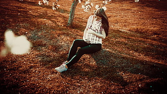 Pregnant woman sitting under blooming tree in park
