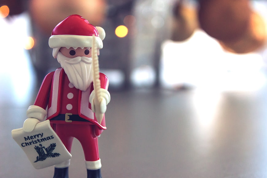 Close-up of Santa Claus toy holding Merry Christmas card