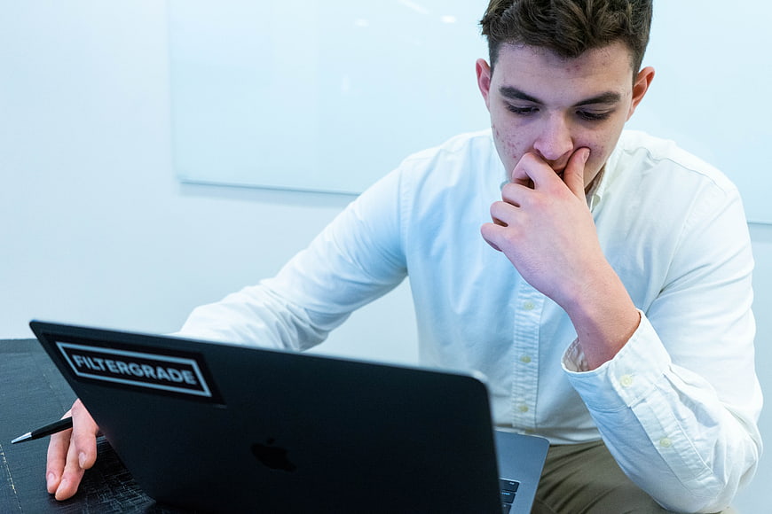 Young Man Thinking at Laptop in Office