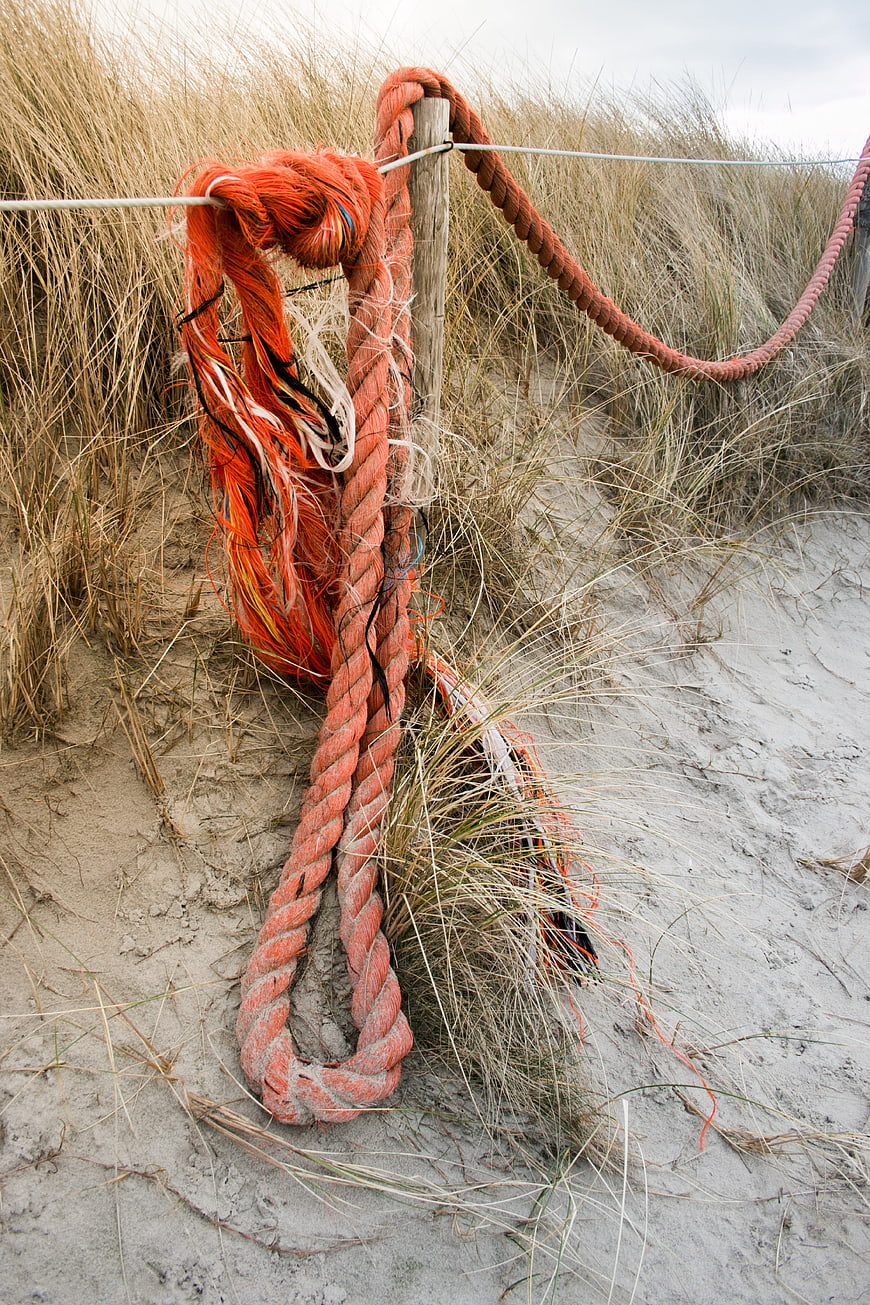 Worn Orange Rope on Wooden Post in Sandy Dunes