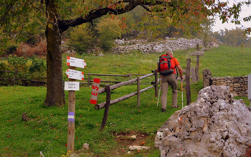 Hiker with backpack walking on E5 trail in autumn Lessinia Italy