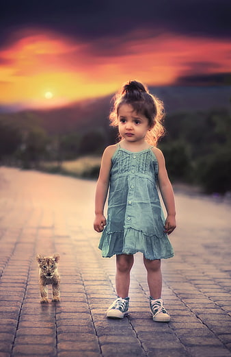 Little Girl Standing with Lion Cub at Sunset