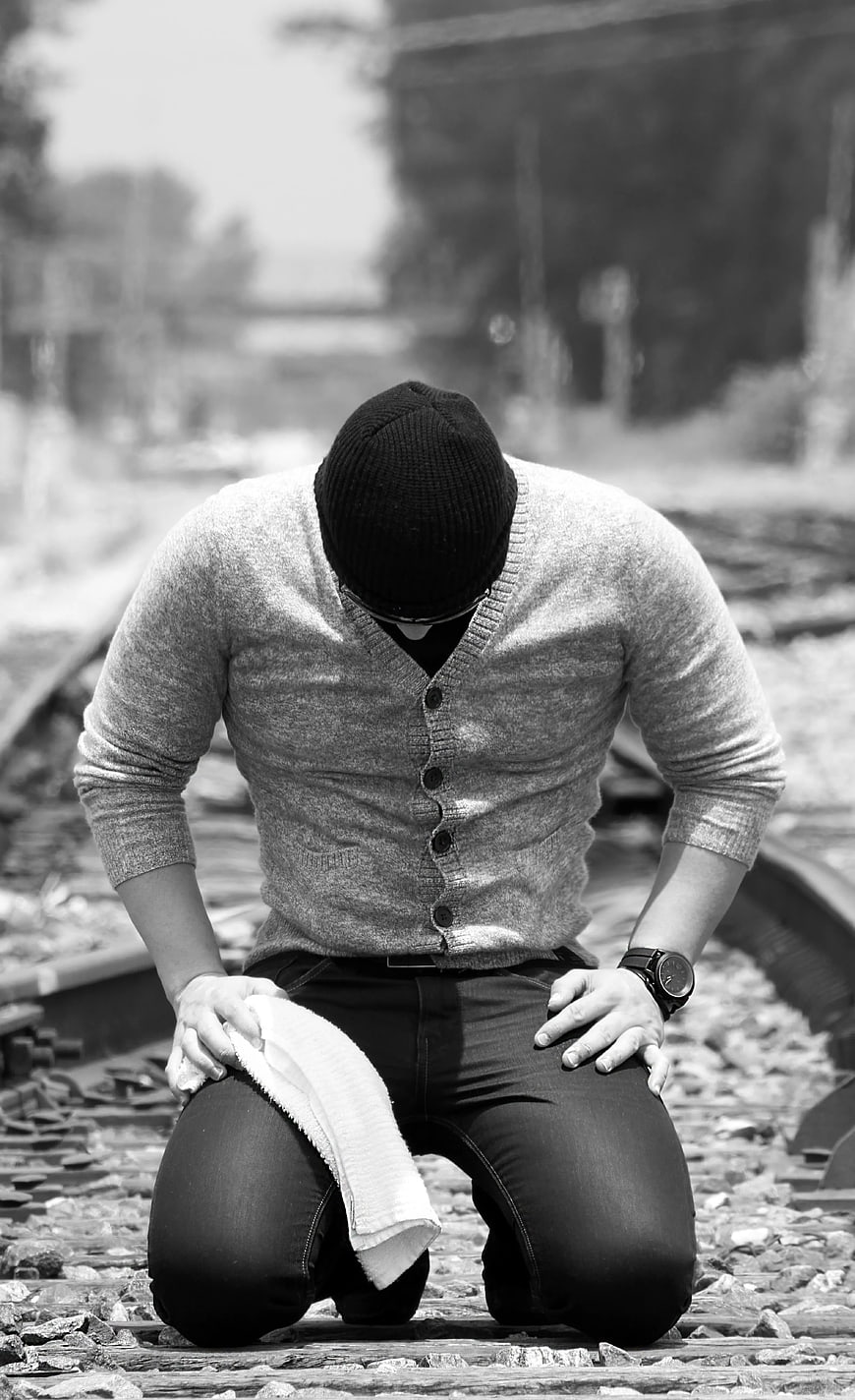 Man Kneeling on Train Tracks in Black and White