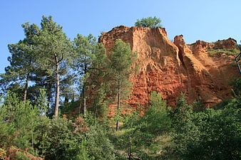 Red ochre cliff face with pine trees in Provence landscape
