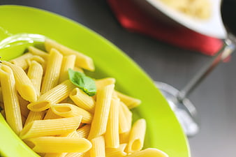 Close-up of penne pasta on a bright green plate