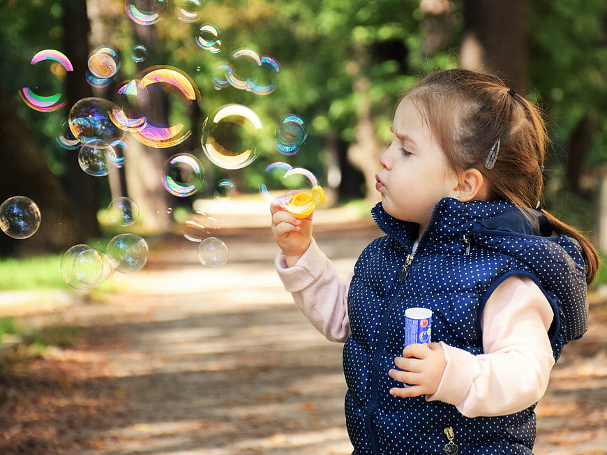 Little Girl Blowing Soap Bubbles in a Park