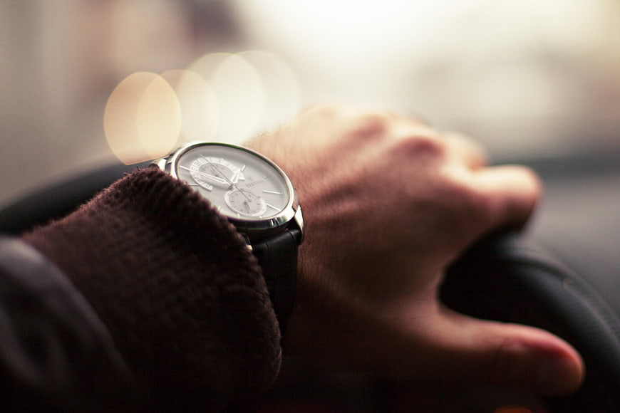 Close-up of a man's wrist wearing a luxury watch while driving a car