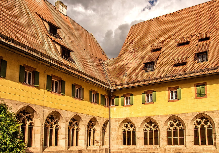 Historic yellow monastery courtyard with Gothic arches and tiled roof