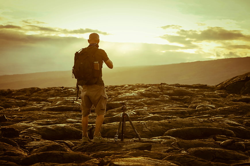 Photographer with Tripod on Rocky Landscape at Sunset