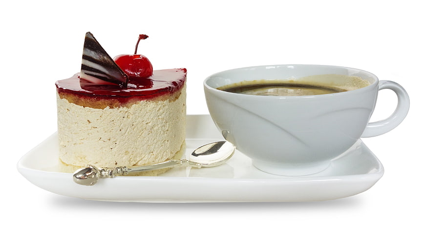 Cheesecake with cherry and coffee cup on white plate