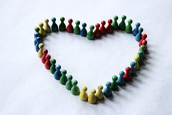 Colorful Wooden People Figurines Arranged in Heart Shape on White Background