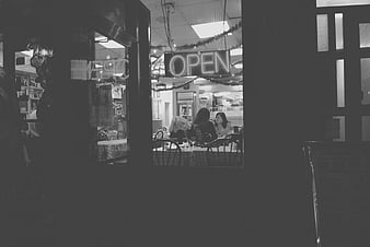 Black and white photo of women dining in a cafe with open sign