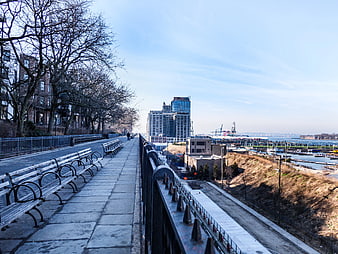 Urban waterfront promenade with benches and city skyline