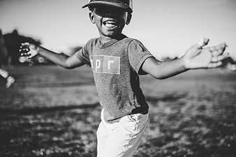 Happy boy running with arms outstretched in black and white