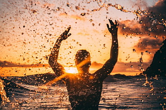 Silhouette of Man Splashing Water at Golden Sunset