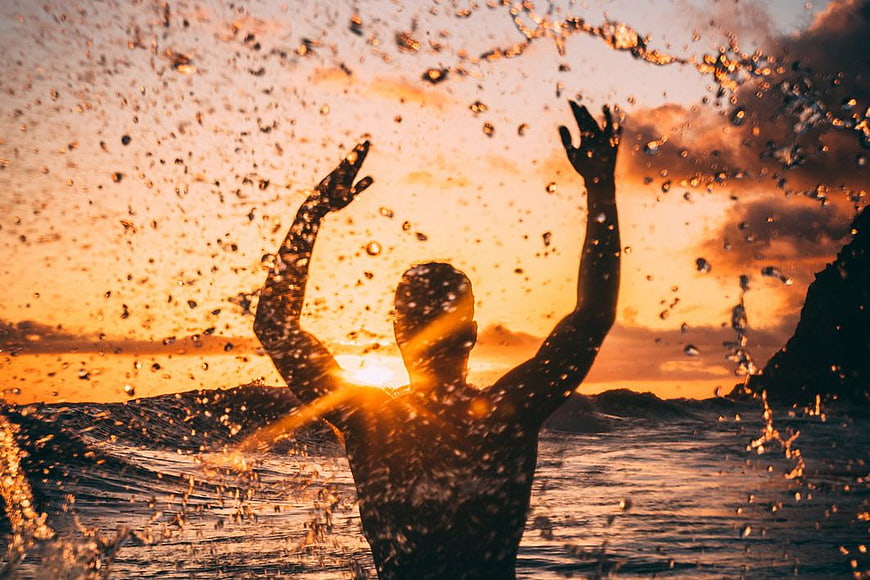 Silhouette of Man Splashing Water at Golden Sunset