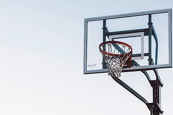 Outdoor basketball hoop and net against a bright overcast sky