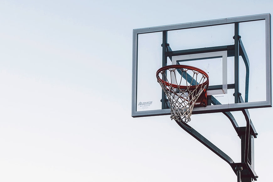 Outdoor basketball hoop and net against a bright overcast sky