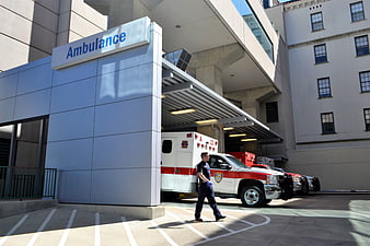 Hospital Ambulance Bay With EMT Walking Near Parked Emergency Vehicle