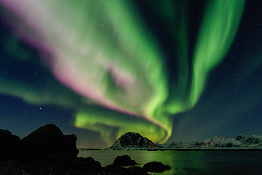 Vibrant Green and Pink Aurora Borealis Over Snowy Mountains