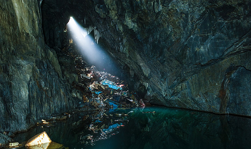 Abandoned cars in a dark cave with a beam of light
