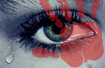 Close-up of eye with red handprint and tears