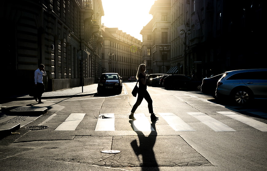 Woman crossing street in golden hour sunlight